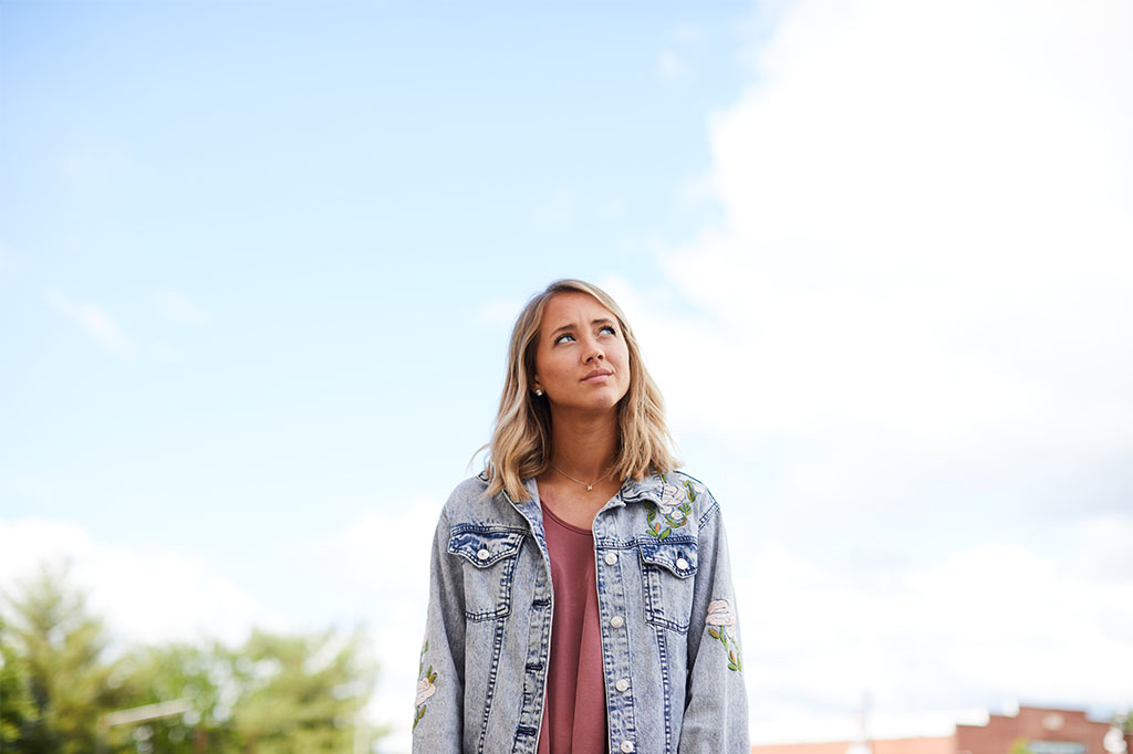 Young woman outside looking up to the sky.